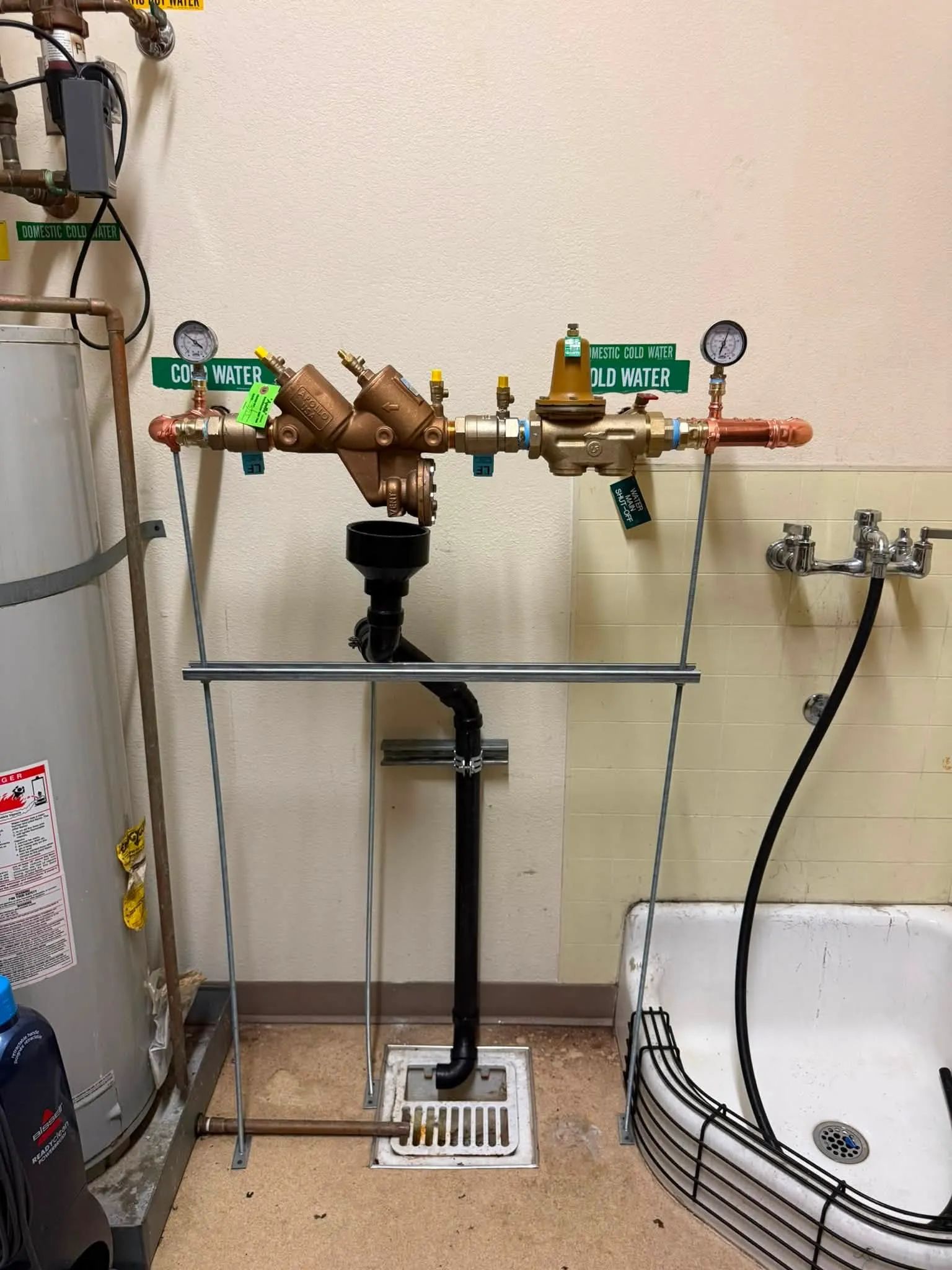 Water heater with connected plumbing pipes, valves, and water lines in a utility room.